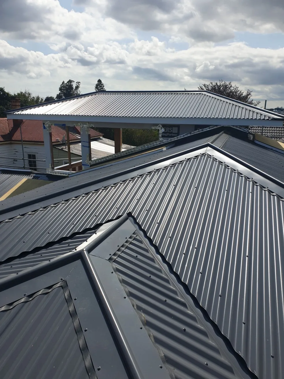 grey longrun metal roof ridge against a blue sky