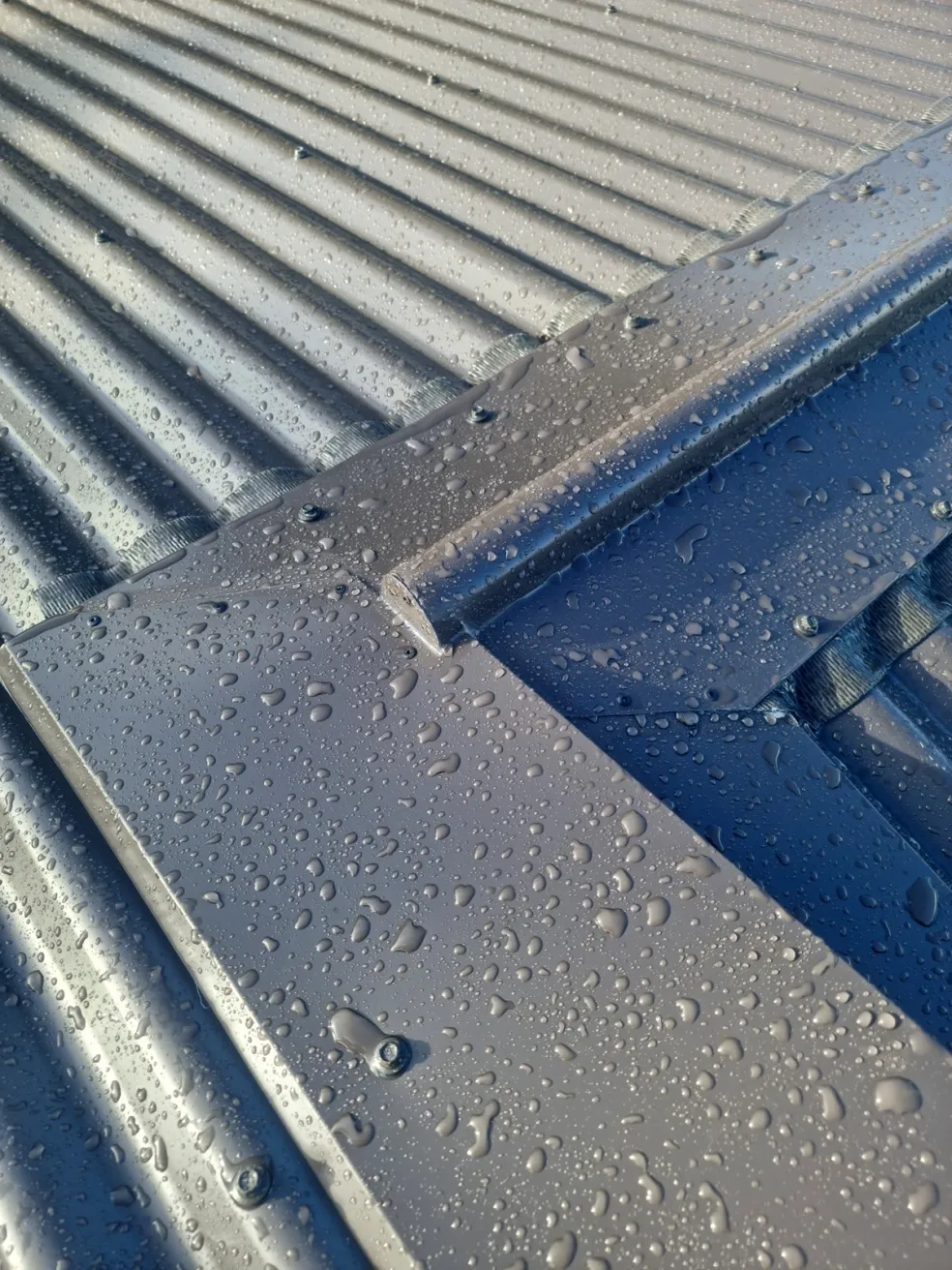 water beading on a dark metal roof surface